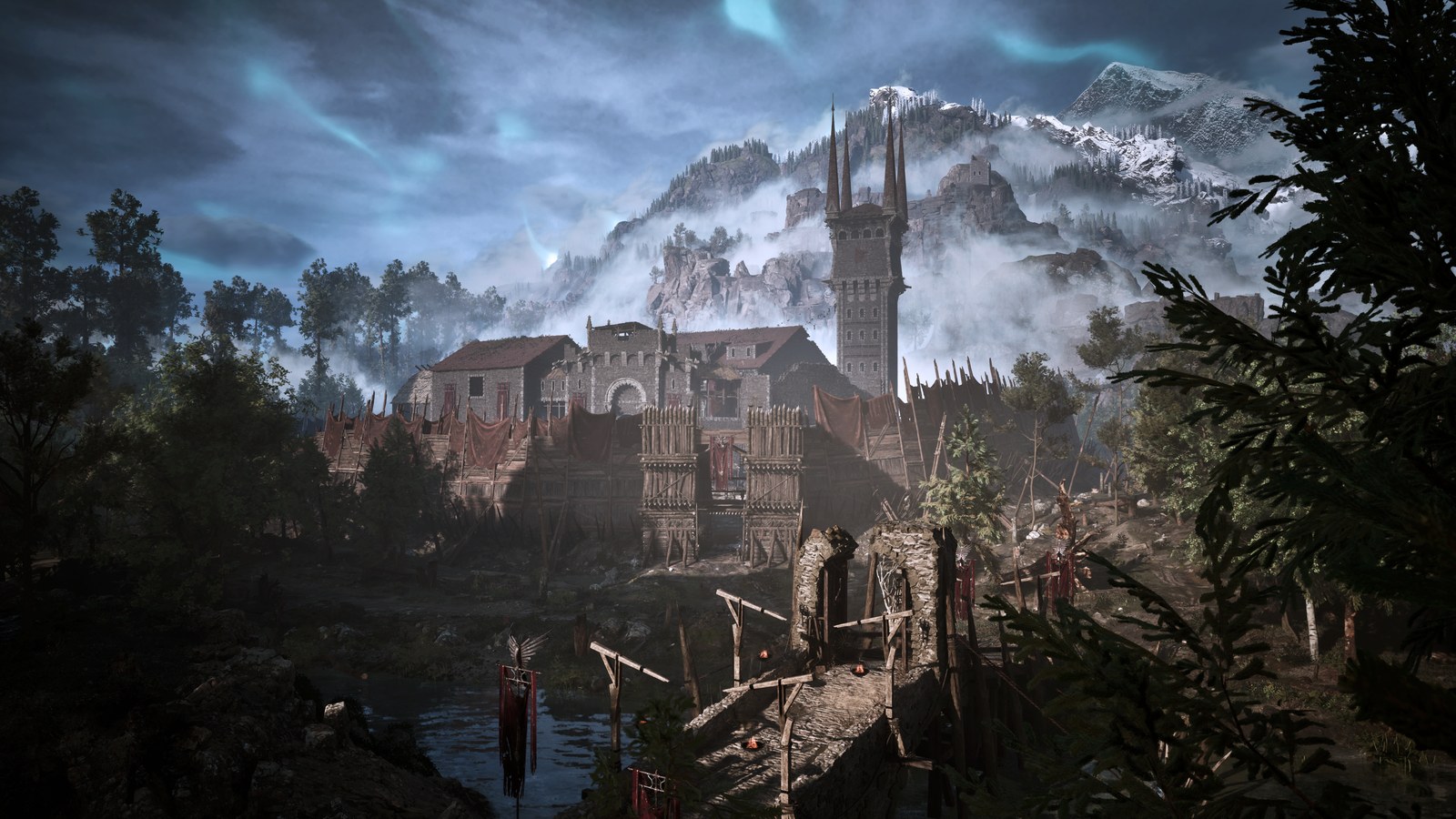 A walled fort in Gothic 1 Remake: a stone keep with a tall spired tower behind a wooden palisade hung with red cloth, a stone bridge with torches and wooden posts in the foreground, dark trees on either side, and misty snow-capped mountains under a cloudy sky streaked with pale blue light