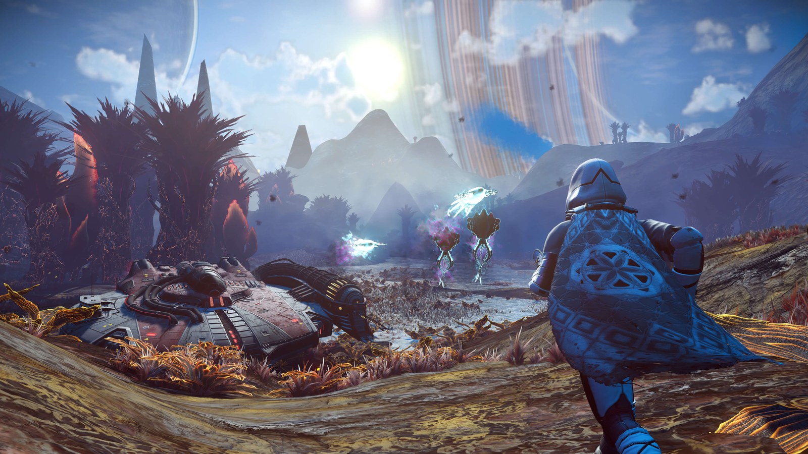 A No Man's Sky explorer in a patterned blue cape running across a rust-coloured alien plain past a crashed starship, towards glowing floating creatures, with tall dark plants and a huge banded planet in the hazy sky