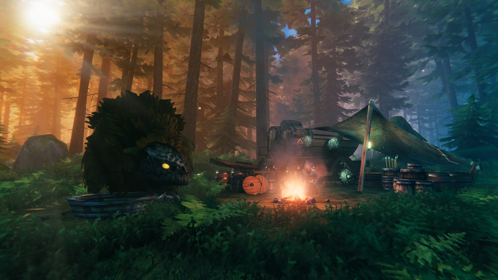 A Valheim camp at dusk in a pine forest: a campfire burning in front of a low tent slung between poles, barrels and a round wooden shield stacked beside a laden cart, a wooden tub in the foreground, and a large shaggy dark creature with a single yellow eye standing at the left among ferns, with low sun breaking through the trunks behind